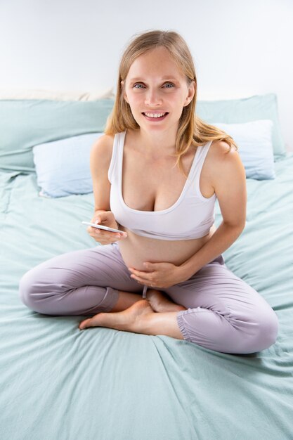 Cheerful expectant mom using online mobile app