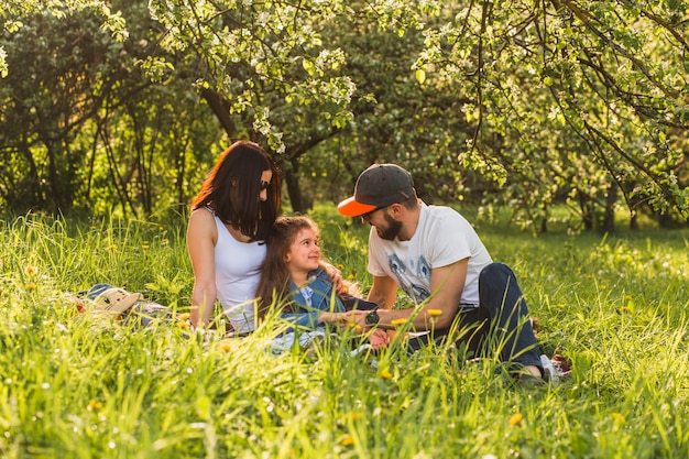 Cheerful family sitting on grass in green park