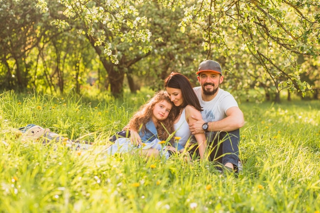 Cheerful family sitting in green grass during summer