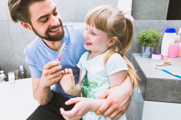 Cheerful father and daughter brushing teeth