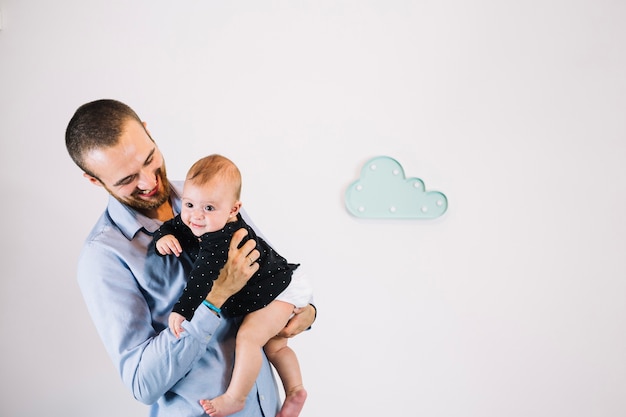 Cheerful father looking at baby