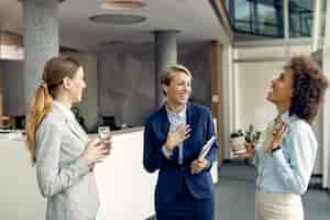 Free photo cheerful female business colleagues having fun while talking in a hallway