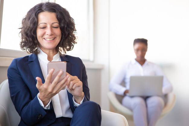 Cheerful female employee watching content on cell