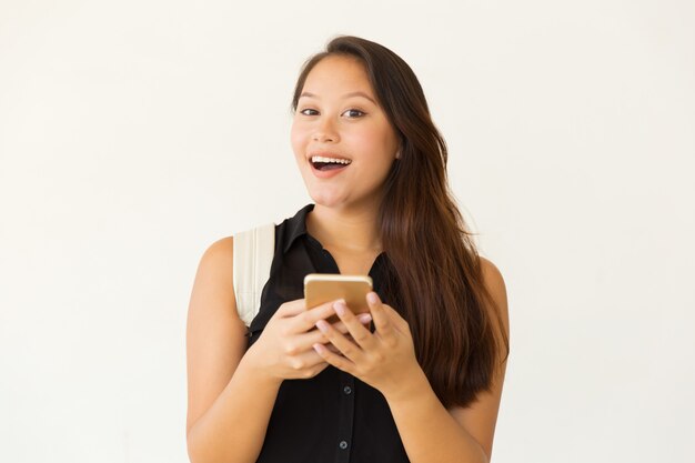 Cheerful female student using smartphone