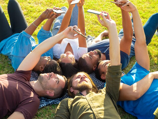 Cheerful friend lying and using smartphones