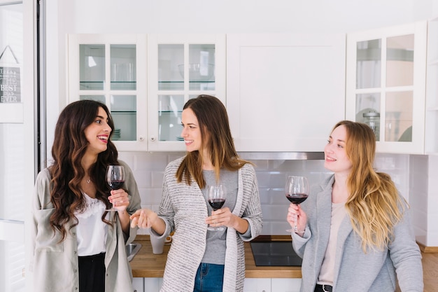 Free photo cheerful friends drinking wine in kitchen