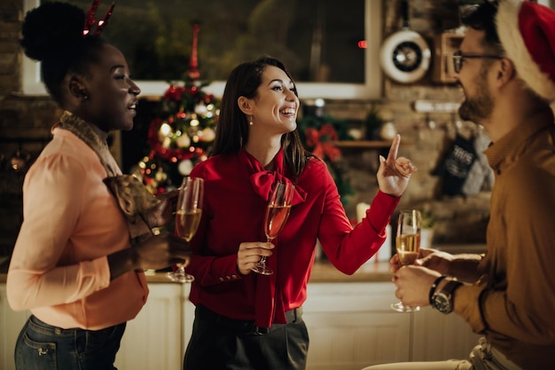 Cheerful friends having fun while drinking Champagne and talking on New Year's eve at home