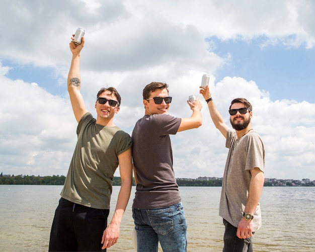 Cheerful friends raising hands with beer