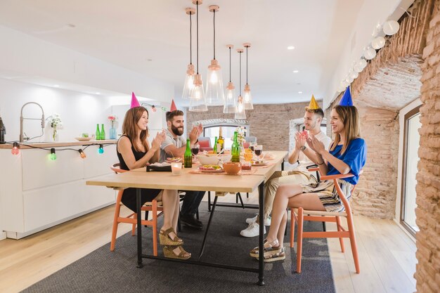 Cheerful friends sitting at table and applauding