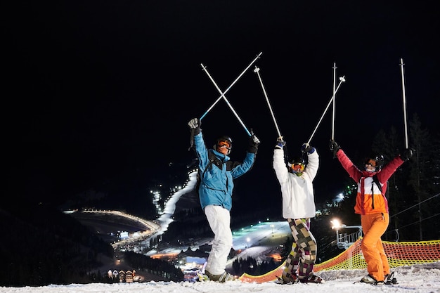 Cheerful friends skiing at ski resort at night