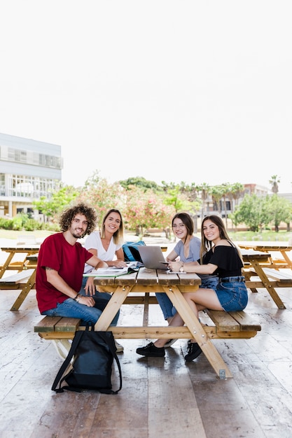 Cheerful friends studying at park table