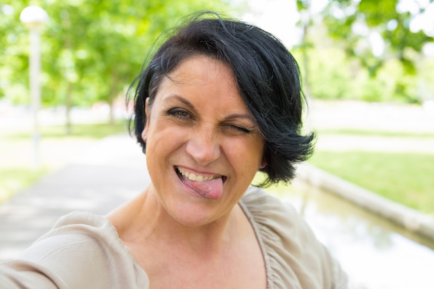 Cheerful funny woman grimacing and taking selfie