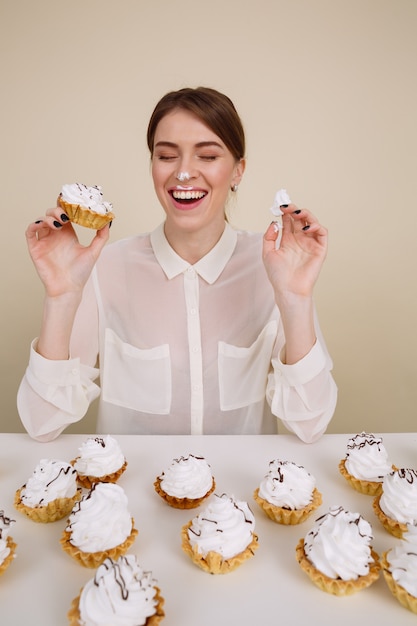 Free photo cheerful funny young woman eating cakes and laughing