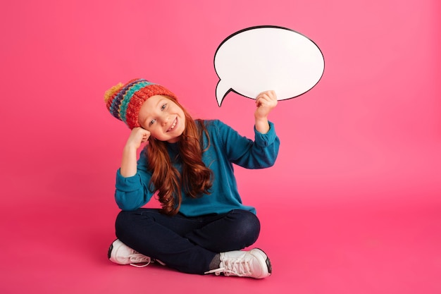 Cheerful ginger girl holding bubble speech and looking camera