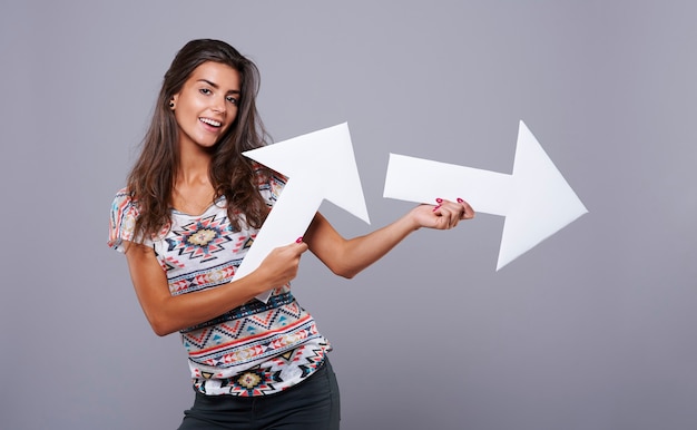 Cheerful girl holding vertical and horizontal arrow signs