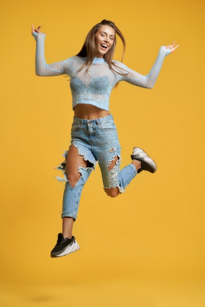 Free photo cheerful girl in jump raising leg up