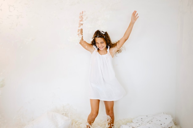 Free photo cheerful girl jumping under falling feathers