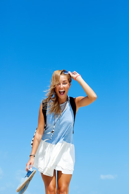 Cheerful girl laughing and holding her sandals