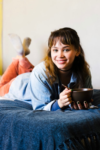 Cheerful girl lying with bowl