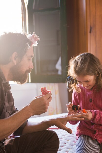 Cheerful girl painting father's nails