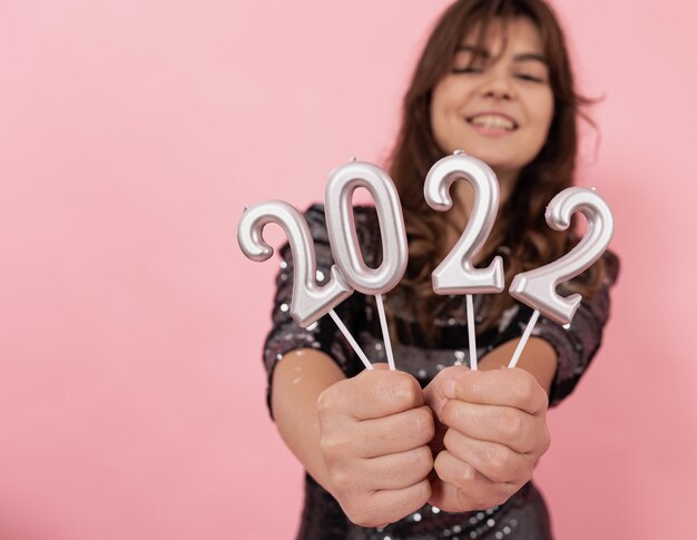 A cheerful girl on a pink background holds the numbers  in her hands