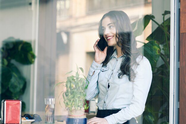 Cheerful girl talking on the phone in a restaurant