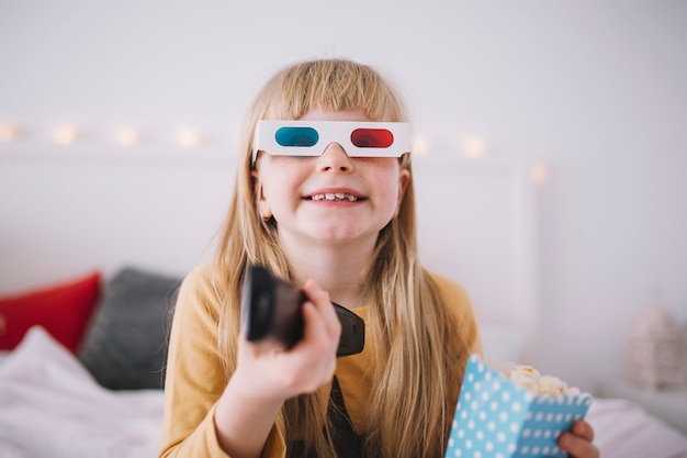 Cheerful girl watching TV in bedroom