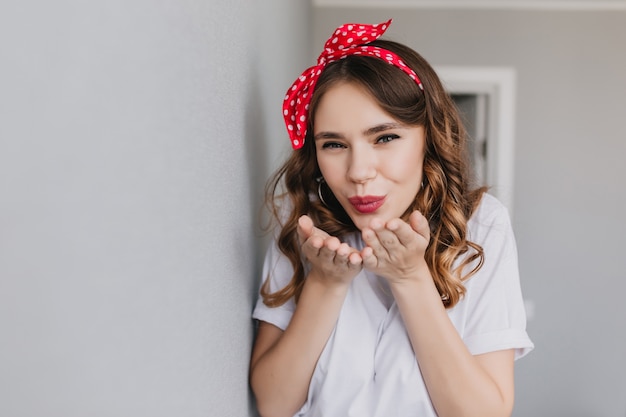 Free photo cheerful girl with curly light-brown hair posing. adorable white young woman sending air kiss.