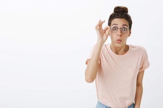 Cheerful girl with glasses posing against the white wall