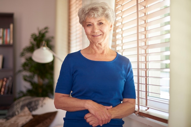 Free photo cheerful grandmother standing next to the window