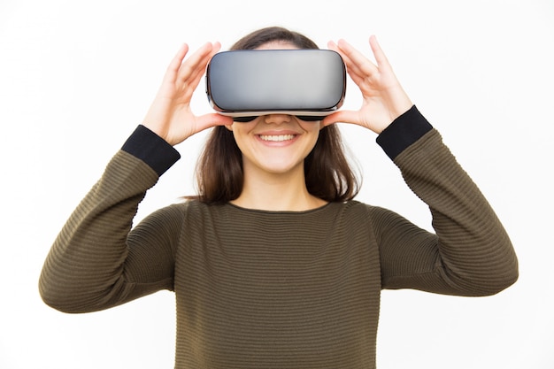 Cheerful happy gamer in VR headset touching device