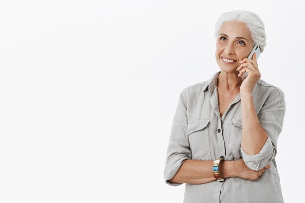 Cheerful happy grandmother talking on mobile phone and smiling