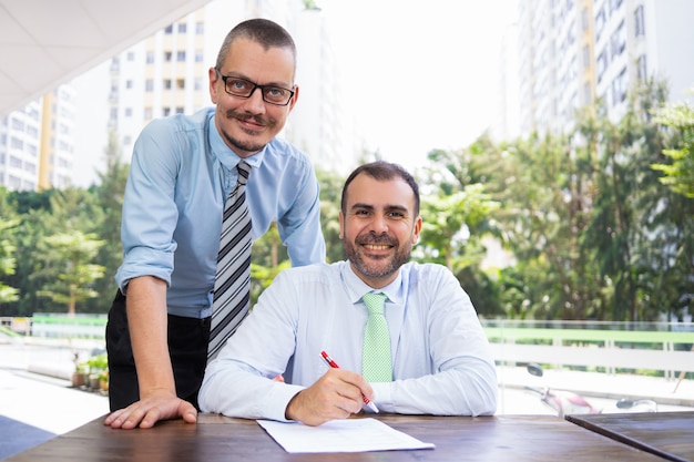 Cheerful Hispanic businessman and assistant looking at camera