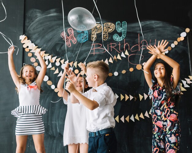 Free photo cheerful kids releasing balloons on birthday party