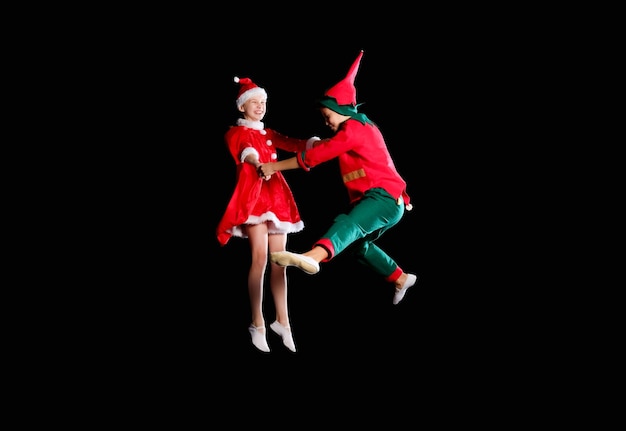 Cheerful kids - A young girl wearing a Santa's costume and boy wearing elf costume flying together