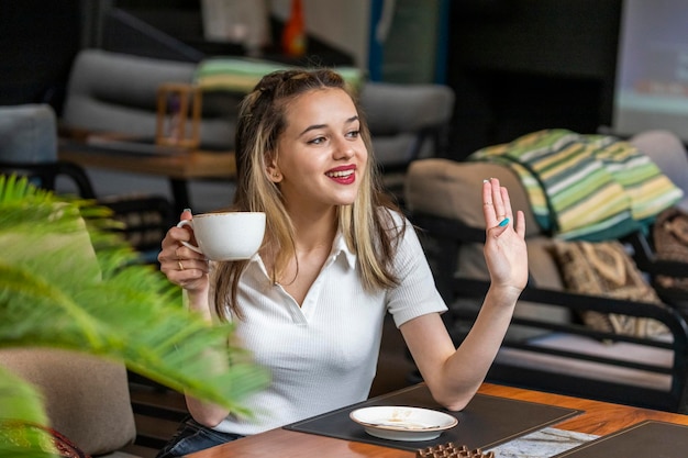 Cheerful lady holding coffee cup and shaking her hand aside