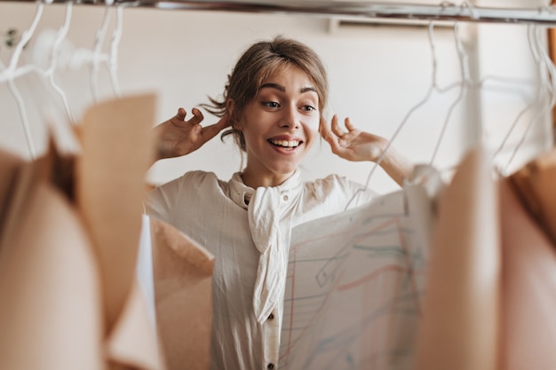 Cheerful lady in stylish outfit looks with proud at her clothing samples