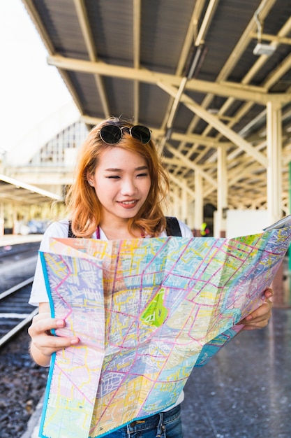 Free photo cheerful lady with map on platform