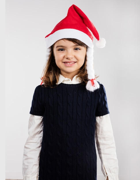 Free photo cheerful little girl posing with a santa hat