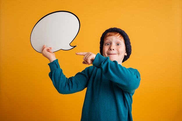 Cheerful little redhead boy holding speech bubble.