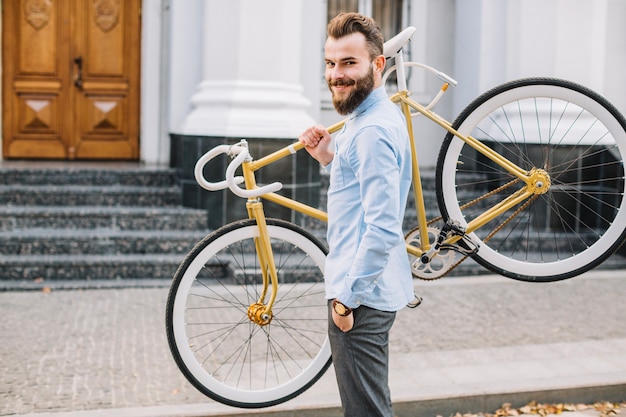 Free photo cheerful man carrying bicycle on shoulder