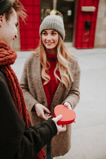 Cheerful man gifting heart box to girlfriend