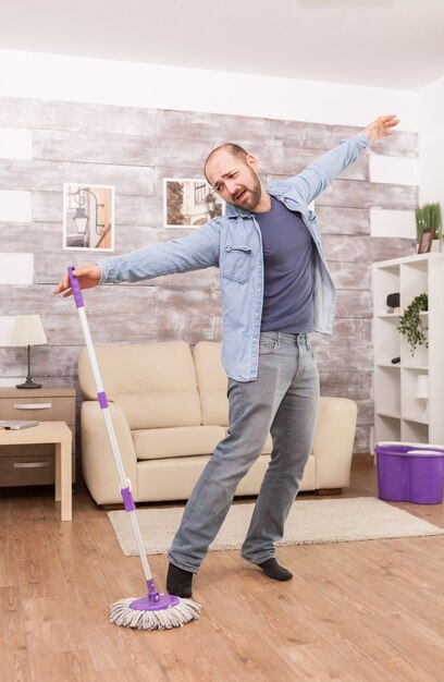 Cheerful man having fun mopping apartment floor