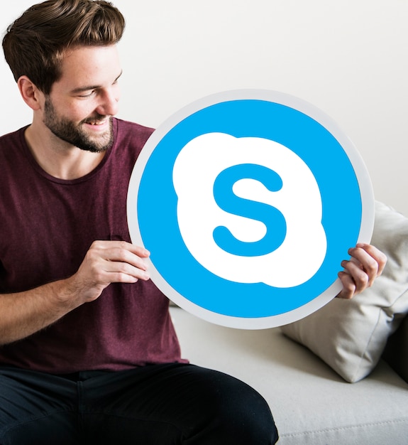 Free photo cheerful man holding a skype icon