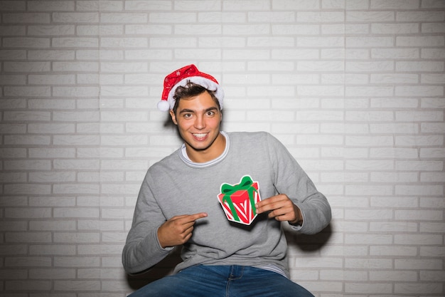 Free photo cheerful man pointing at christmas present