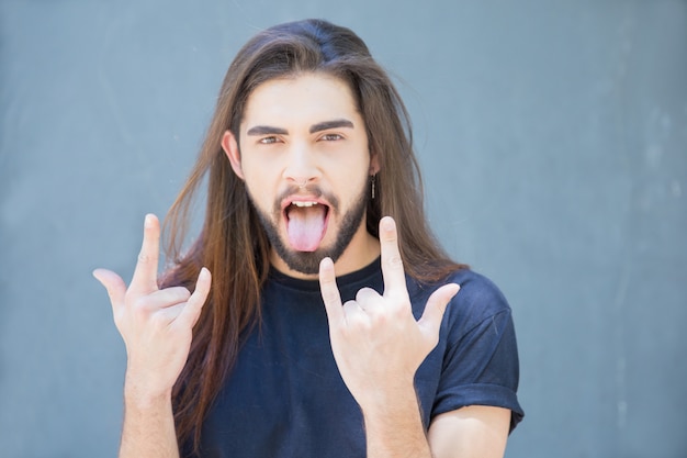 Free Photo cheerful man showing rock gesture to express success