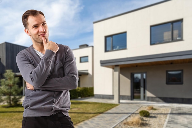 Cheerful man standing in front of new house.