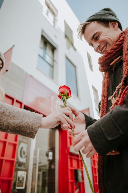 Free photo cheerful man taking rose gift