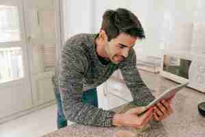 Free photo cheerful man using tablet in kitchen