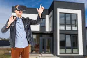 Free photo cheerful man in virtual glasses in front of new house.